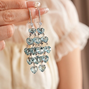 Detailed close-up of light blue heart crystal tassel earrings with sparkling silver chains