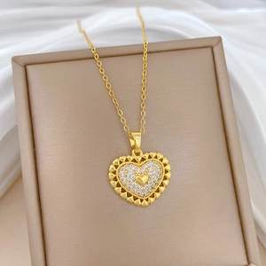 Gold heart necklace with hollow edge and diamond center on brown display stand