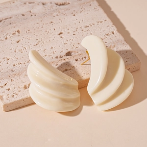 Close-up of cream resin layered geometric earrings on stone textured background