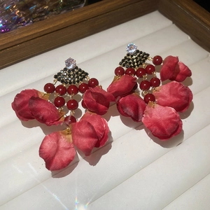 Close-up of red fabric flower petal tassel earrings with sparkling crystal accents