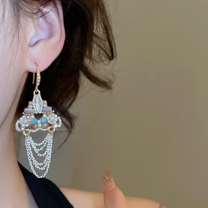 Close-up of vintage gold tassel earrings with colorful rhinestones and pearls on model