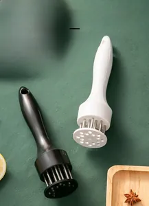 Detail of stainless steel meat tenderizer needles with ergonomic handle in kitchen setting