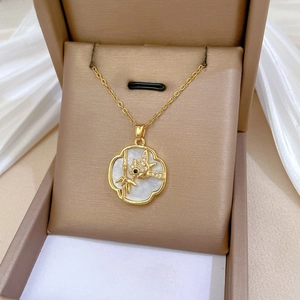 Detailed close-up of shell necklace with bamboo and bird engraving on champagne silk