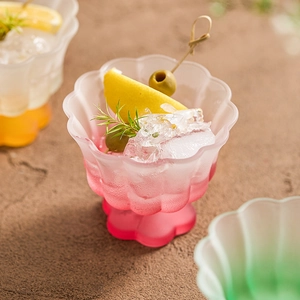 Gradient pink frosted glass petal-shaped bowl with ice cubes and lemon garnish