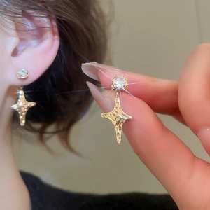 Macro shot of gold star earrings with hammered texture and sparkling zircon studs