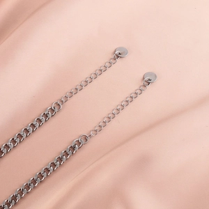 Paire de bracelets gourmette en acier argenté pour couples sur un fond en soie rose