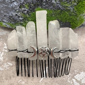 Close-up of clear crystal comb with black metal wire, pentagram, and moon charms