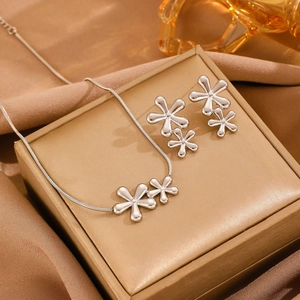 Detailed view of silver flower necklace and earrings set displayed on a gold gift box