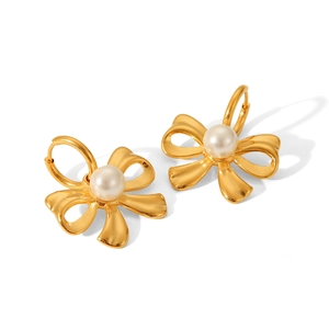Macro shot of 18K gold plated bowknot earrings with white pearl detail on white background