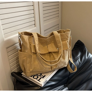 Detail of khaki corduroy tote bag showing soft texture and front pockets on a sofa