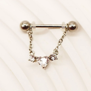 Macro detail of stainless steel heart piercing jewelry with hanging zirconia chain