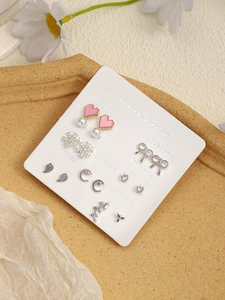 Detail view of 7-day stud earring set with pink heart, snowflake, and pearl motifs