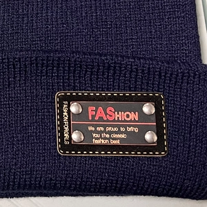 Detailed macro view of dark blue ribbed knit beanie with riveted fashion patch