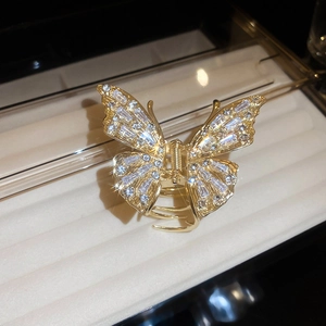 Close-up of golden butterfly hair claw clip with sparkling rhinestones on satin tray