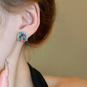 Close-up of rainbow square crystal earring with small diamonds on model's ear