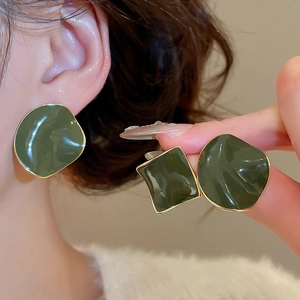 Detail view of dark green enamel earrings with irregular wavy gold edges and glossy finish