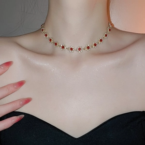 Close-up of golden floral necklace with red gemstones and crystals on neck