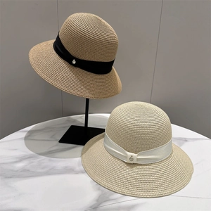 Close-up of woven straw sun hats featuring elegant ribbon bands and metallic charms