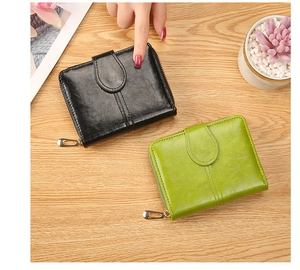 Flat lay of black and green bifold wallets with zipper on a wooden table with plants
