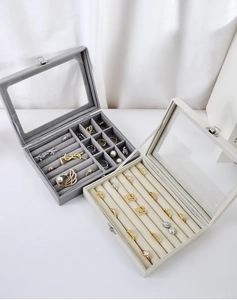 Detail view of grey and beige velvet jewelry boxes with glass lids and metal buckles