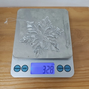 Detail shot of acrylic snowflake pendant weighing 32.8g on a digital scale
