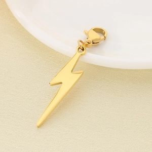 Close-up of golden lightning bolt charm with lobster clasp on a textured background