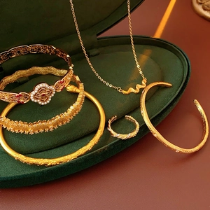 Close-up of vintage gold jewelry set with ruby and pearl in a green velvet box