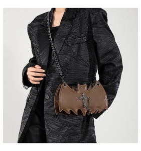 Brown bat-shaped jelly crossbody bag with gothic cross charm worn over a black blazer