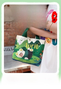 Detail of canvas tote bag showing green handle, snap button, and outdoor cartoon print