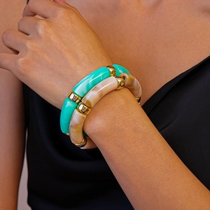 Détail de joncs en résine marbrée verte et beige avec perles dorées au poignet
