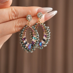 Gros plan de boucles d'oreilles bohèmes dorées avec cristaux colorés et perles rétro
