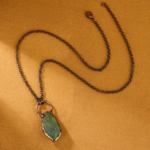 Dettaglio del ciondolo in fluorite verde grezza con avvolgimento in rame antico