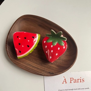 Close-up of cute acrylic strawberry and watermelon hair clips on a wooden tray