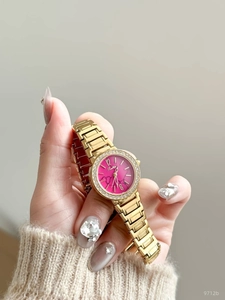 Vue détaillée d'une montre dorée en strass avec cadran en marbre rose sur le poignet