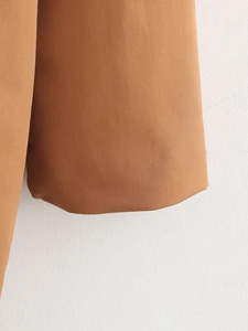 Macro shot of dark caramel twill woven fabric on a long casual open coat's sleeve detail