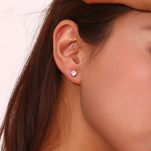 Close-up of a minimalist 18K gold plated stud earring with a round white zircon on ear