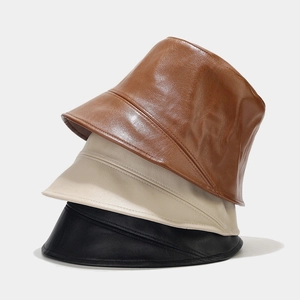 Stack of PU leather bucket hats in brown, cream, and black colors for a minimalist style