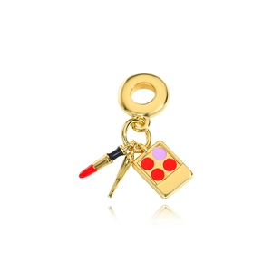Macro detail of gold charms featuring lipstick, makeup brush, and eyeshadow palette on a ring