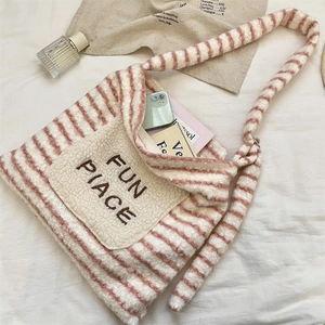 Gros plan du sac cabas pelucheux à rayures roses et crème avec écusson brodé