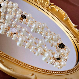 Detail of multilayer baroque pearl necklace with enamel camellia flower charms