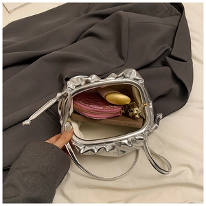 Top view of metallic silver pleated bag showing interior capacity with wallet and lipstick