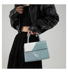 Gros plan d'un sac à main bicolore bleu clair et blanc avec texture crocodile chic