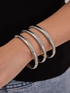 Détail d'un ensemble de trois bracelets argentés sertis de zircons portés au poignet