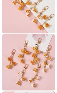 Detailed macro of realistic PVC popcorn keychain with golden lobster clasp on pink background