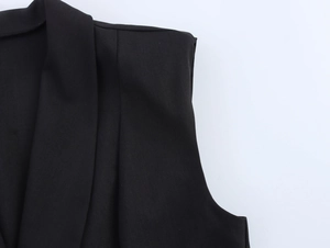 Detail of shoulder seam and neckline tailoring on black sleeveless vest with crisp texture