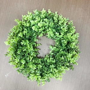 Artificial green money leaf wreath for spring DIY home decor on dark wood background