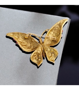 Detailed back view of a golden butterfly brooch with matte finish and safety pin closure