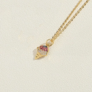 Macro detail of 14K gold plated necklace with zircon studded ice cream cone pendant