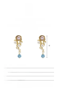 Macro shot of gold plated baroque pearl earrings with blue gemstone detail specifications