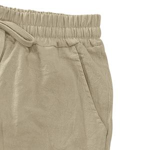 Detail of linen shorts featuring elastic drawstring waistband and side pockets in khaki